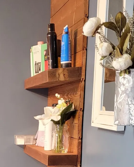 The salon's product shelf on the stained pine wall, bottles and boxes lined up beside the mirrors